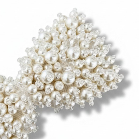 Close up of the handbeading of girls ivory bow hair clip - encrusted with white pearl beads and cut crystals
