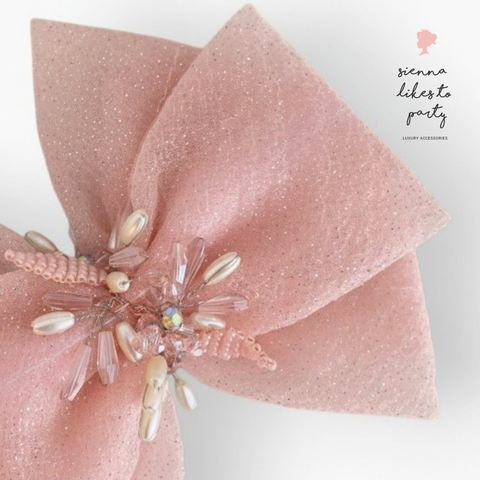 Close up detail of pastel pink designer girls hair bow, showing the diamante, pearls and crystal hand embelishment that draws the bow together.  Designed and created By Sienna Likes to Party