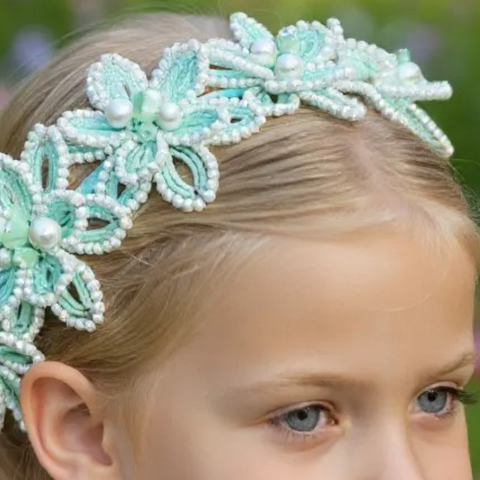 Close-up of a child wearing a handmade soft mint green flower crown surrounded by pearls, perfect for weddings or childrens special occasions